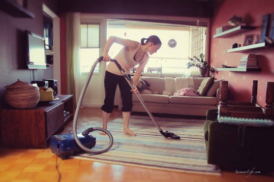 Woman is vacuum cleaning living room carpet on an apartment building