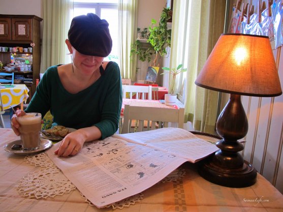 Woman enjoying cup of coffee and reading newspaper