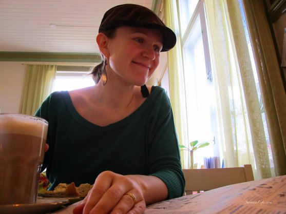 Happy woman enjoying cup of coffee and reading newspaper