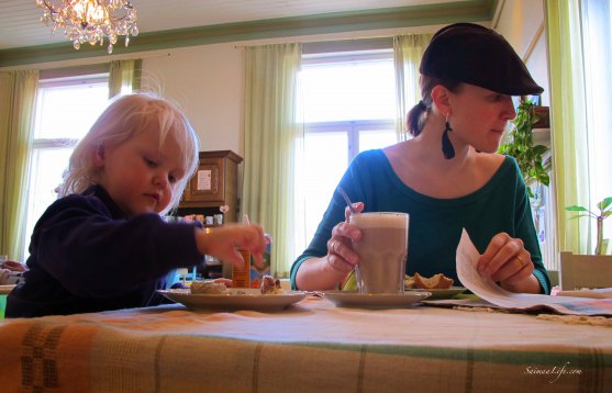 mom and daughter enjoying cup of coffee cafe and reading newspaper