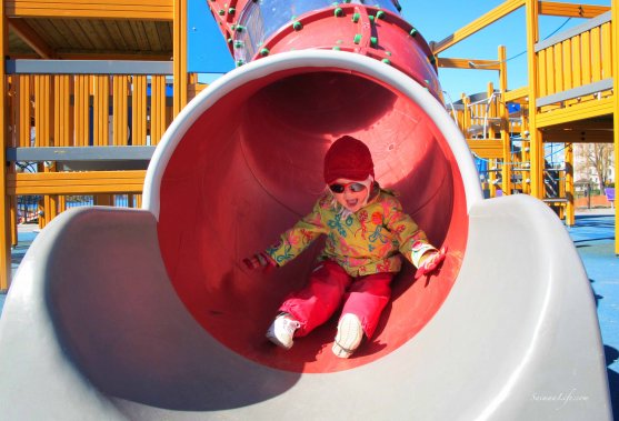 girl sliding through tube playground