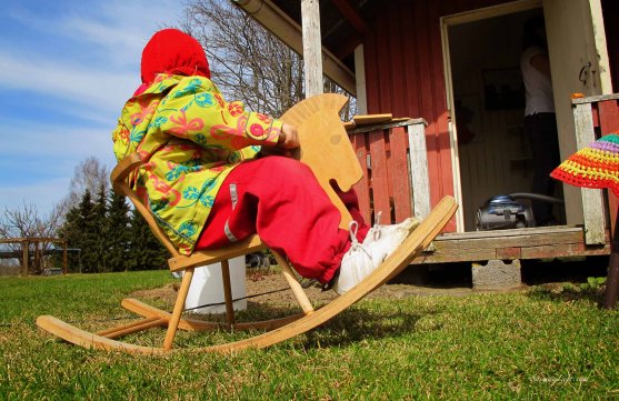 girl riding with wooden horse infront of playhouse