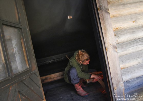 woman-adding-wood-to-finnish-smoke-sauna