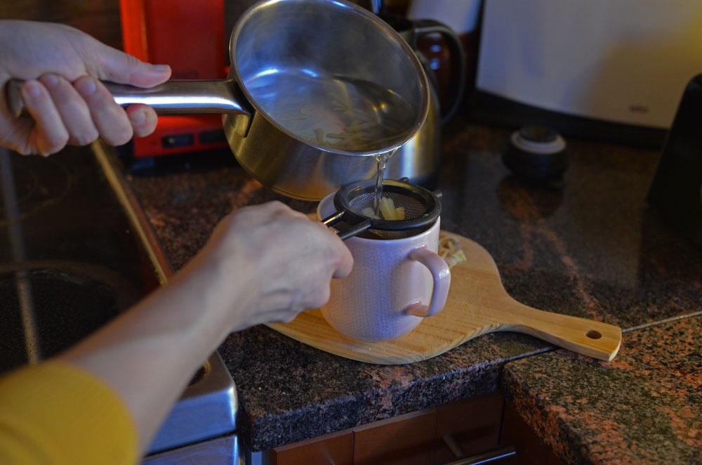 filtering homemade ginger tea for pain relief