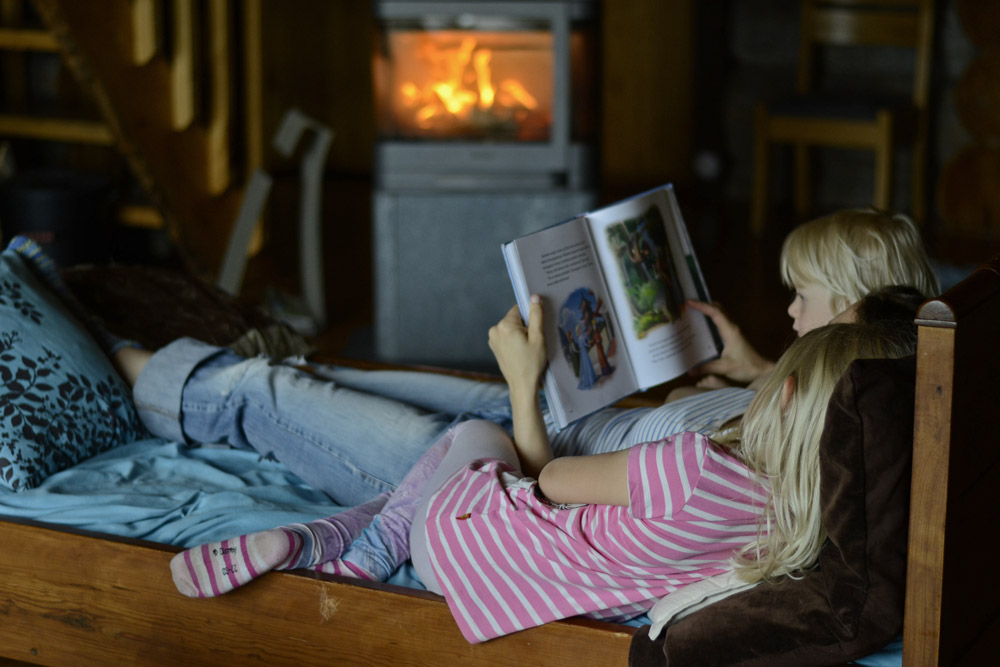 mother-reading-children-book-by-the-fireplace