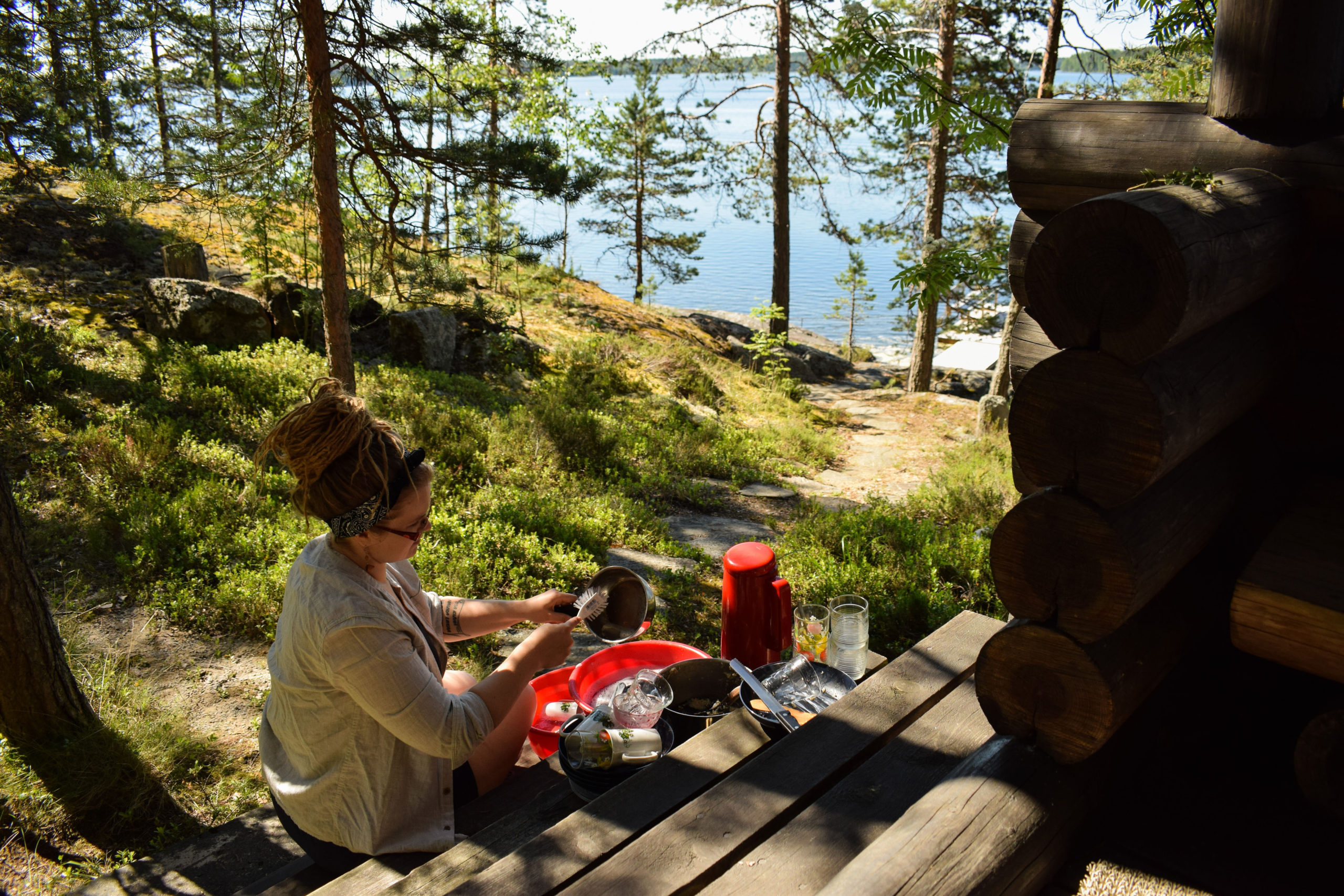 Woman doing dishes outdoors at Kukkoniemen Lomamökit rental cottages in Punkaharju, Saimaa
