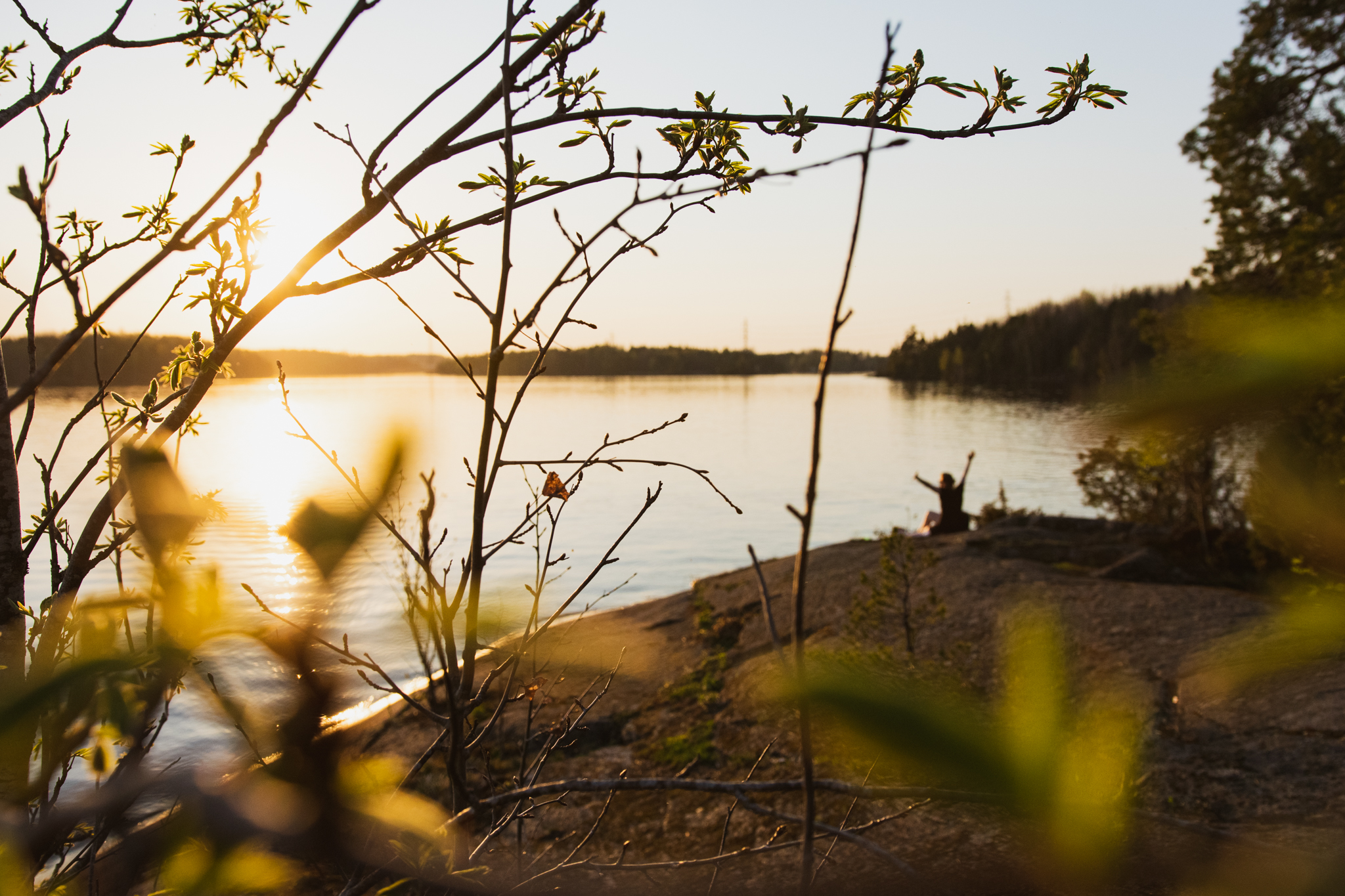 Woman sitting by the lake in spring and watching the sunset in Saimaa, Finland